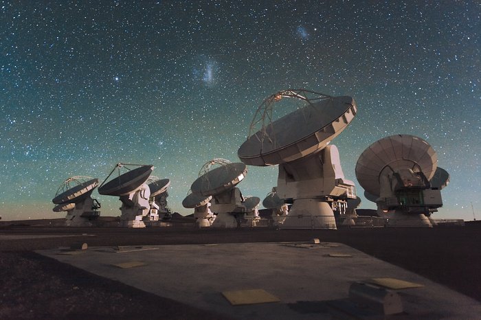 Antennas  of the Atacama Large Millimeter/submillimeter Array (ALMA), on the  Chajnantor Plateau in the Chilean Andes. The Large and Small Magellanic  Clouds, two companion galaxies to our own Milky Way galaxy, can be seen  as bright smudges in the night sky, in the centre of the photograph.